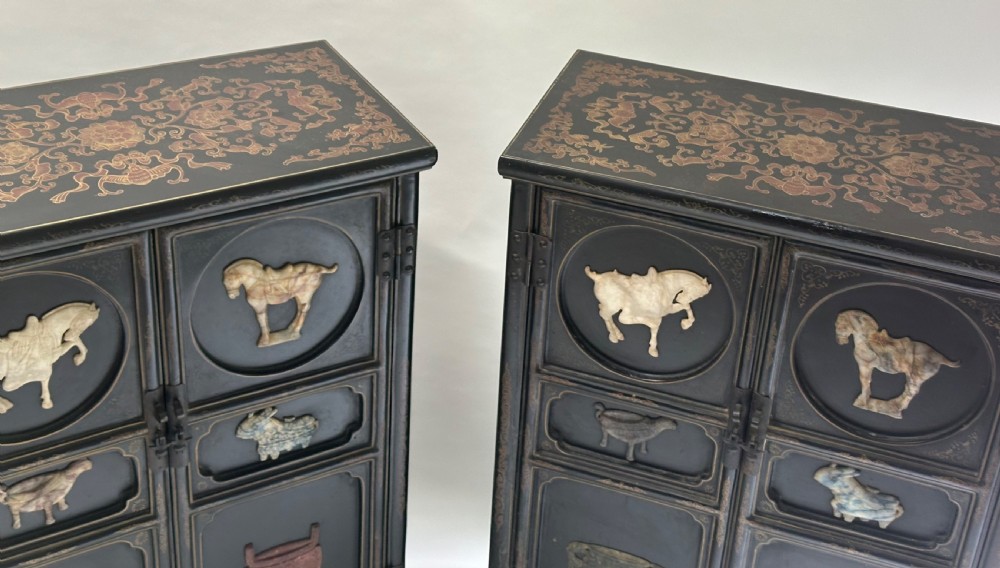 A pair of black lacquered two-door Chinoiserie cabinets featuring carved hardstone inlays of horses, animals, and vessels, topped with gilt scrollwork motifs. View XI