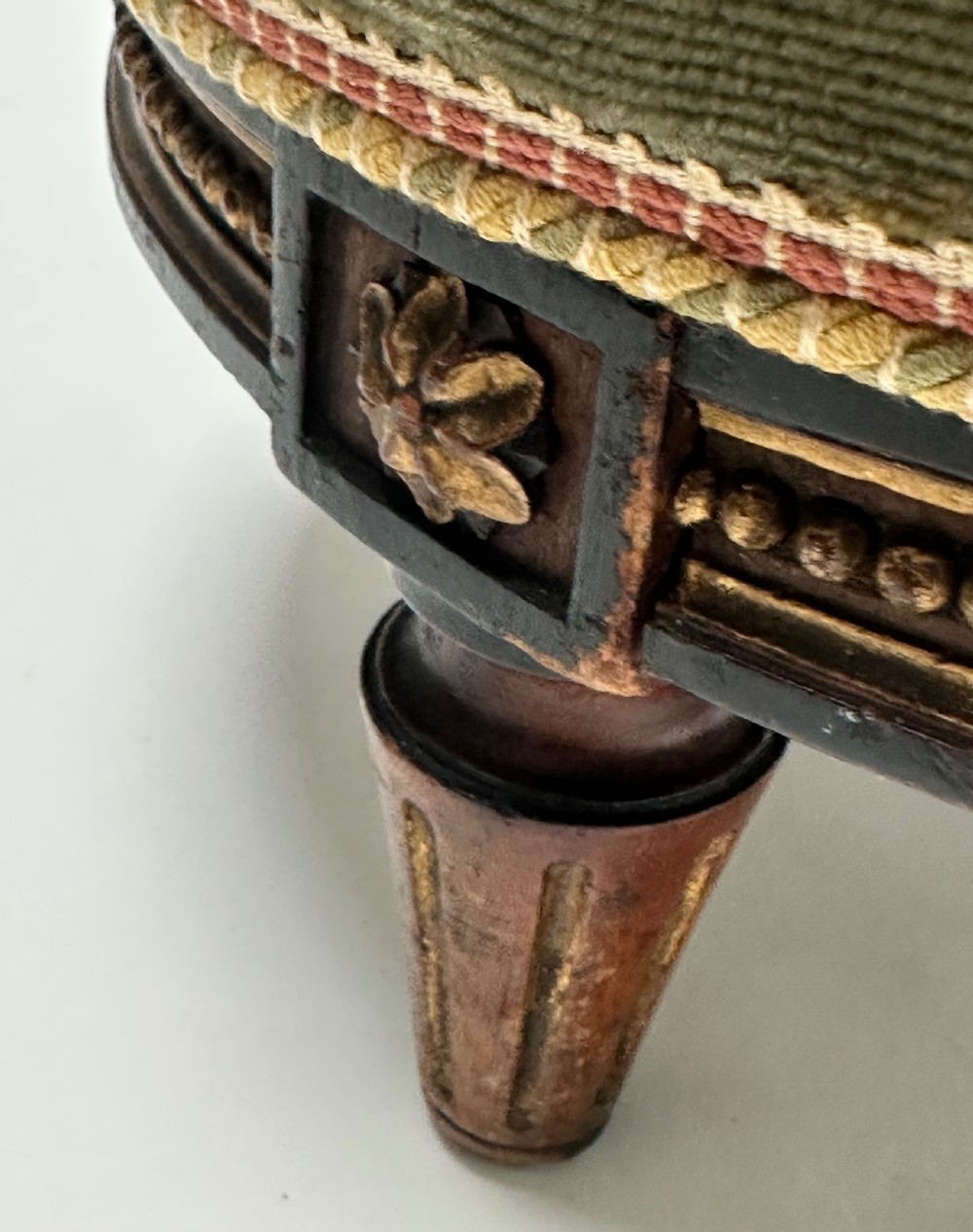 A low circular French footstool featuring a floral needlepoint seat in mustard yellow with green velvet trim and carved wooden legs. View IV