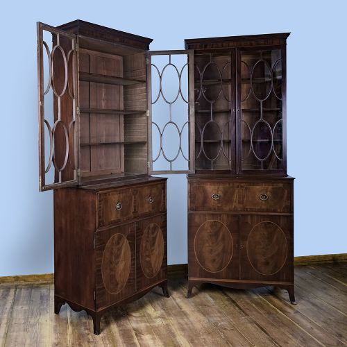 fig 1. A pair of tall George III mahogany bookcases featuring oval astragal glazed upper doors above deep drawers and flame mahogany panelled cupboard bases.