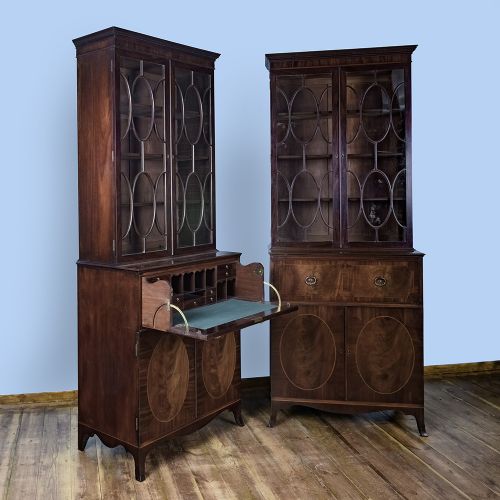 fig 4. A pair of tall George III mahogany bookcases featuring oval astragal glazed upper doors above deep drawers and flame mahogany panelled cupboard bases.