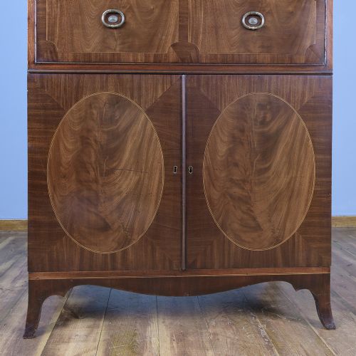 fig 6. A pair of tall George III mahogany bookcases featuring oval astragal glazed upper doors above deep drawers and flame mahogany panelled cupboard bases.
