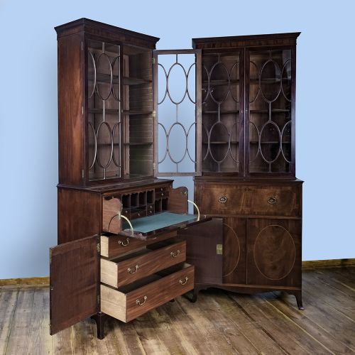 fig 8. A pair of tall George III mahogany bookcases featuring oval astragal glazed upper doors above deep drawers and flame mahogany panelled cupboard bases.