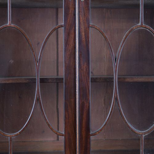 A pair of tall George III mahogany bookcases featuring oval astragal glazed upper doors above deep drawers and flame mahogany panelled cupboard bases. View XIV