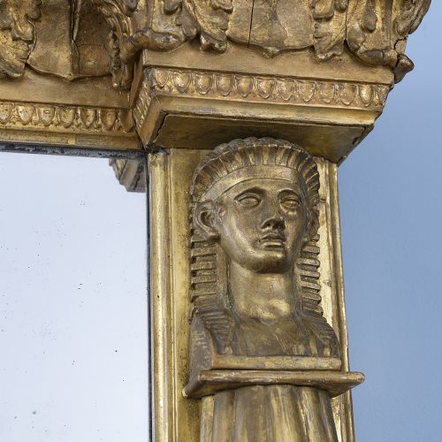 A rectangular Regency giltwood overmantel mirror framed with Egyptian revival term pilasters, sculpted head capitals, and an architectural molded cornice. View IX