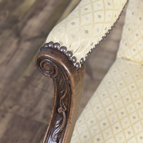 A George III mahogany Gainsborough armchair featuring patterned cream upholstery, brass tack trim, carved serpentine arm supports, and straight legs with brass castors. View VI
