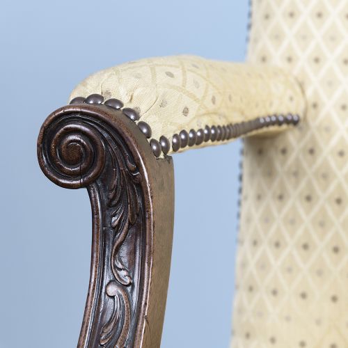 A George III mahogany Gainsborough armchair featuring patterned cream upholstery, brass tack trim, carved serpentine arm supports, and straight legs with brass castors. View XII