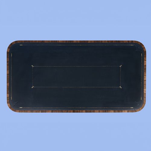A Regency rosewood writing desk featuring a black leather inset surface, frieze drawers, and carved trestle end supports on brass castors. View VII