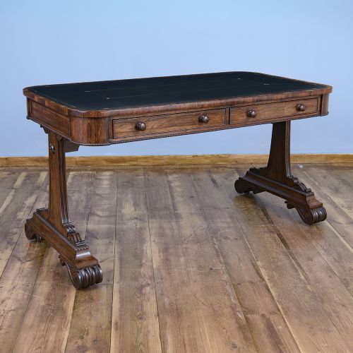 A Regency rosewood writing desk featuring a black leather inset surface, frieze drawers, and carved trestle end supports on brass castors. View XII