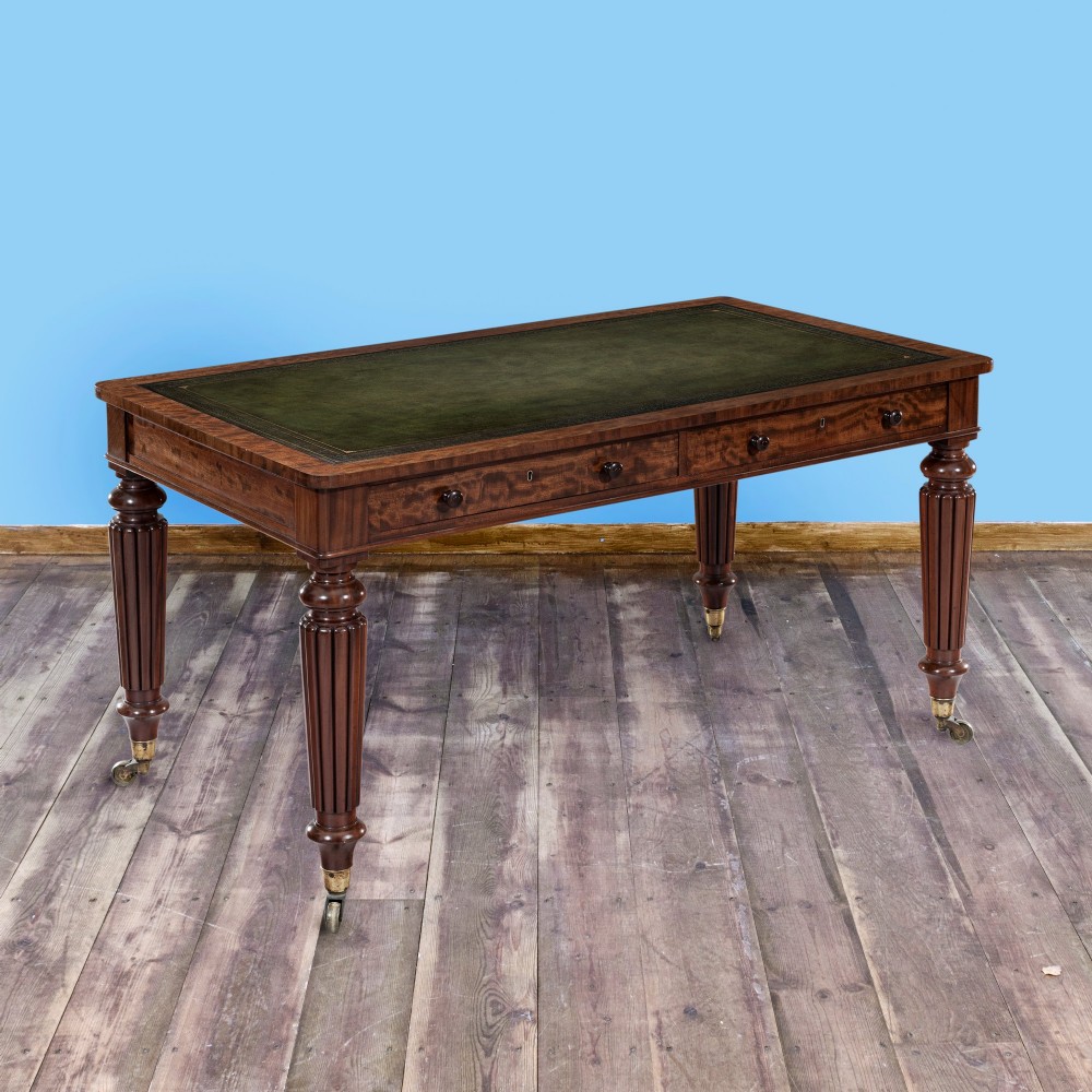 A nineteenth-century mahogany writing table featuring a green leather top, fluted turned legs, and brass castors. View III