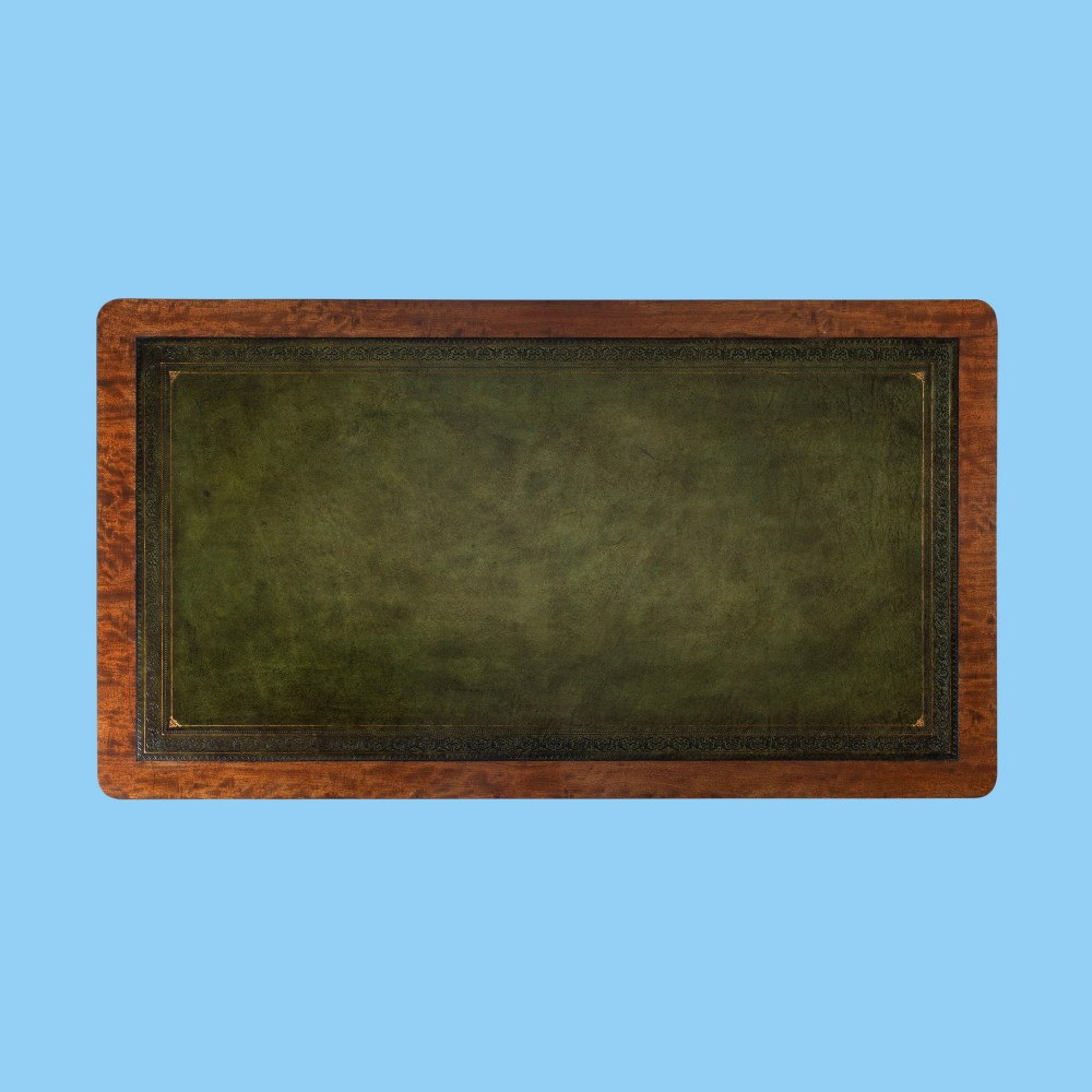 A nineteenth-century mahogany writing table featuring a green leather top, fluted turned legs, and brass castors. View IV