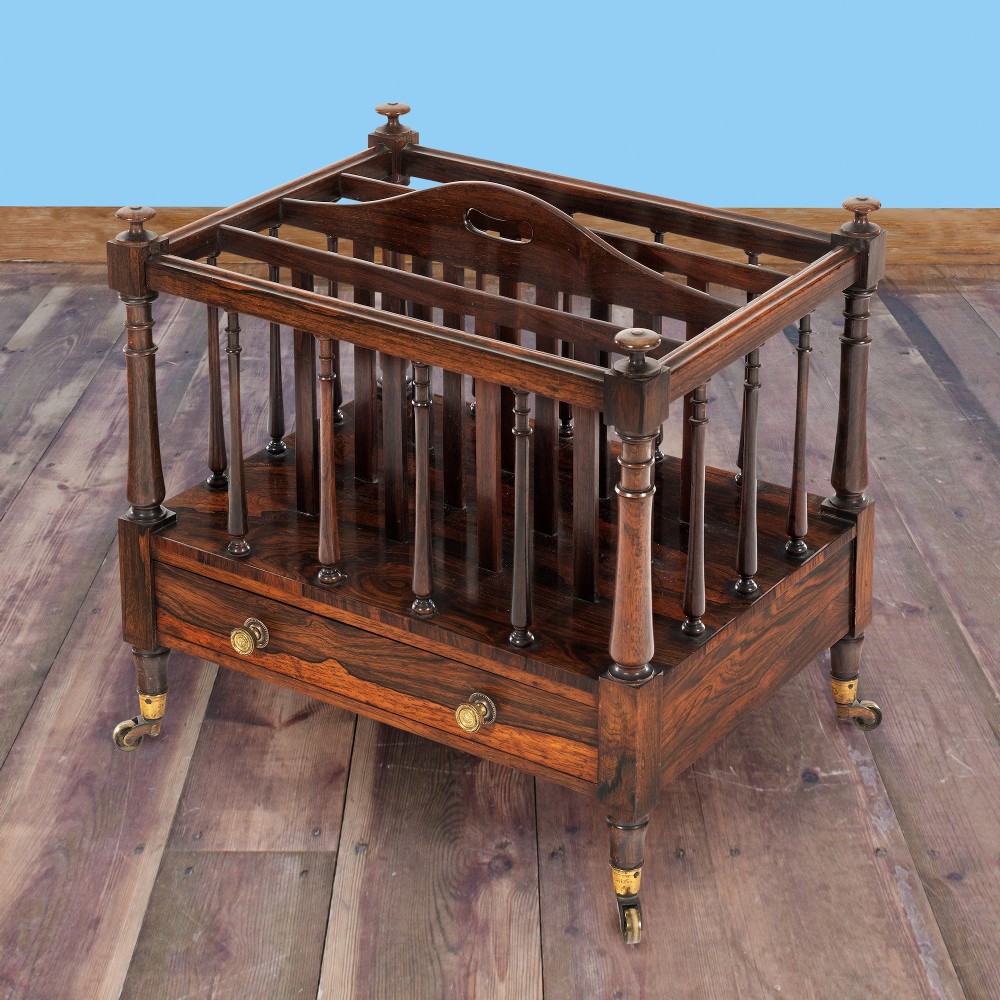 A Victorian rosewood music canterbury featuring turned spindle dividers, a top carrying handle, a lower drawer with two brass knobs, and turned legs with brass castors. View III