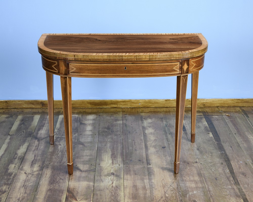 A pair of late 18th-century demi-lune card tables crafted from dark rosewood with contrasting satinwood crossbanding and tapered legs. View V