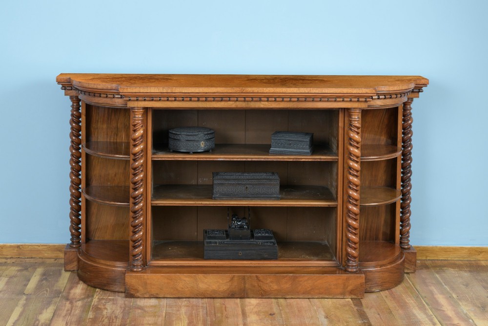 A mid-19th-century burr walnut and amboyna side cabinet featuring open shelves, barley-twist column accents, and a curved breakfront silhouette.