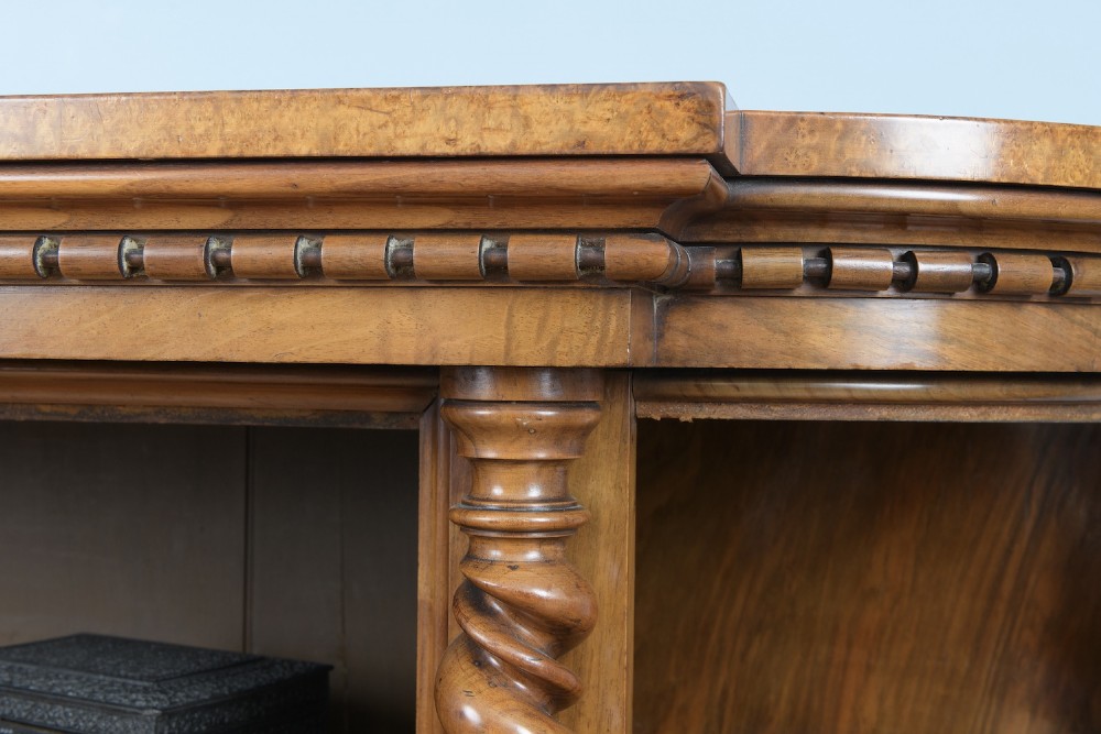A mid-19th-century burr walnut and amboyna side cabinet featuring open shelves, barley-twist column accents, and a curved breakfront silhouette. View VI