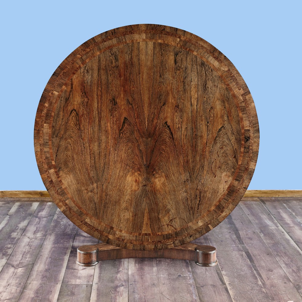 A circular George IV mahogany dining table featuring a sunburst veneer top and a central pedestal on a carved triform base. View III