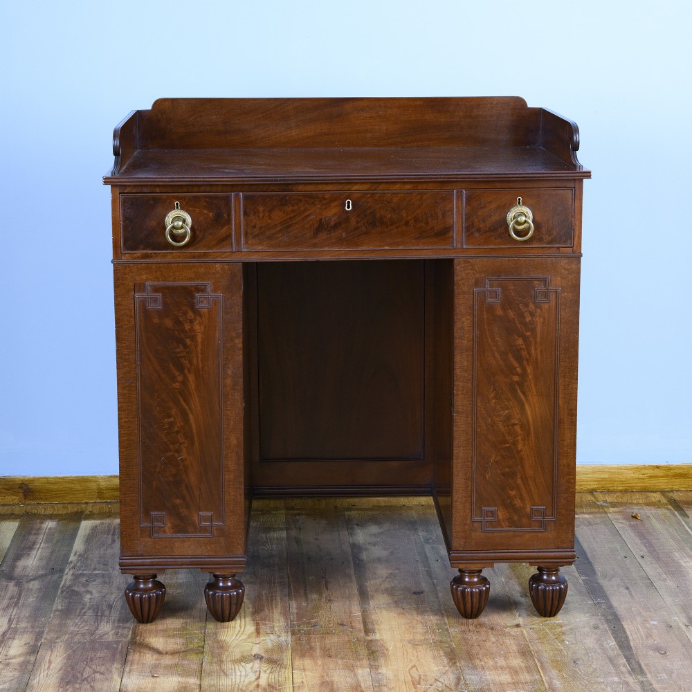 A 19th-century flame mahogany kneehole cabinet featuring brass ring handles, panelled side pedestal doors, and turned reeded feet. View II