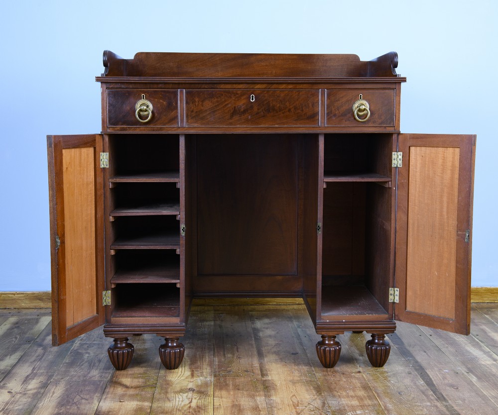 A 19th-century flame mahogany kneehole cabinet featuring brass ring handles, panelled side pedestal doors, and turned reeded feet. View III