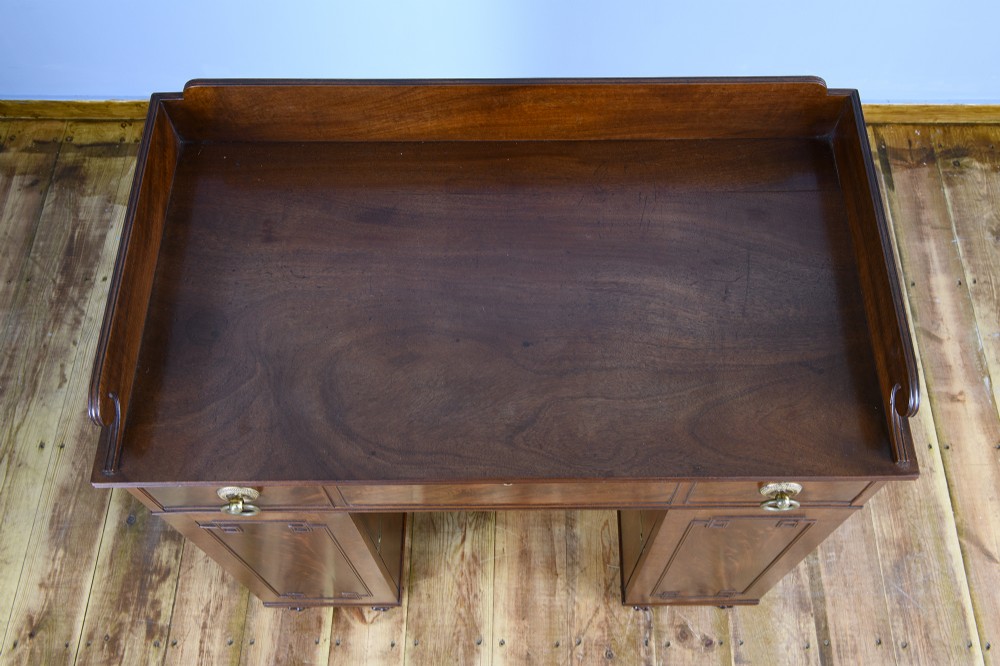 A 19th-century flame mahogany kneehole cabinet featuring brass ring handles, panelled side pedestal doors, and turned reeded feet. View V