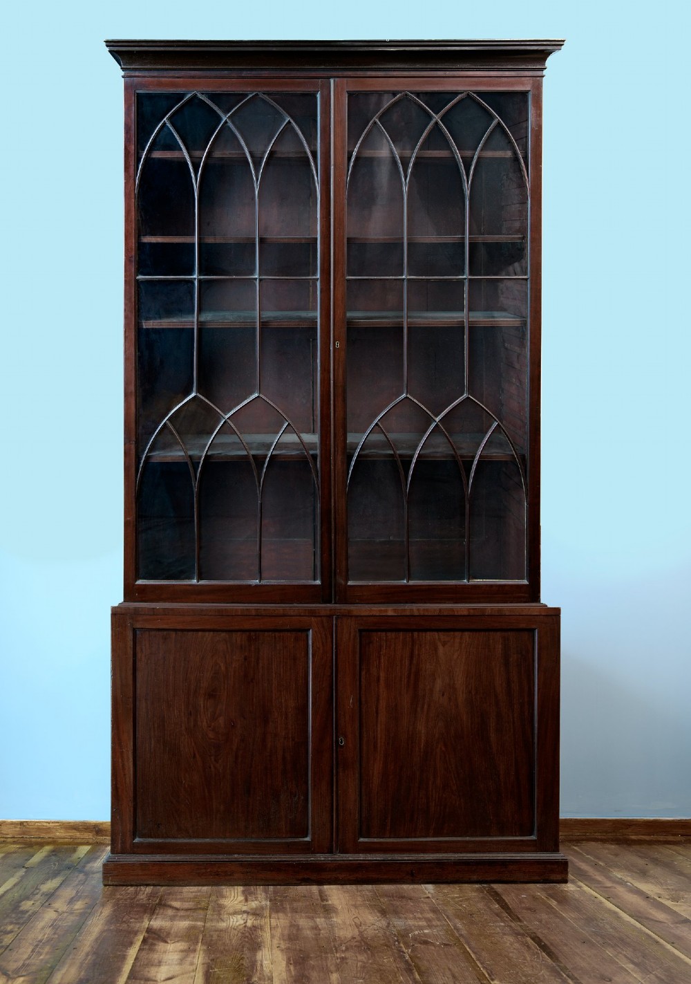 An 18th-century George III mahogany library bookcase featuring two upper glazed doors with Gothic astragal bars and two lower panelled cupboard doors.