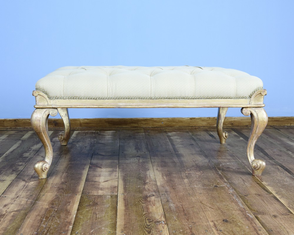 A large William IV style footstool with button-tufted cream upholstery and carved parcel gilt cabriole legs. View II