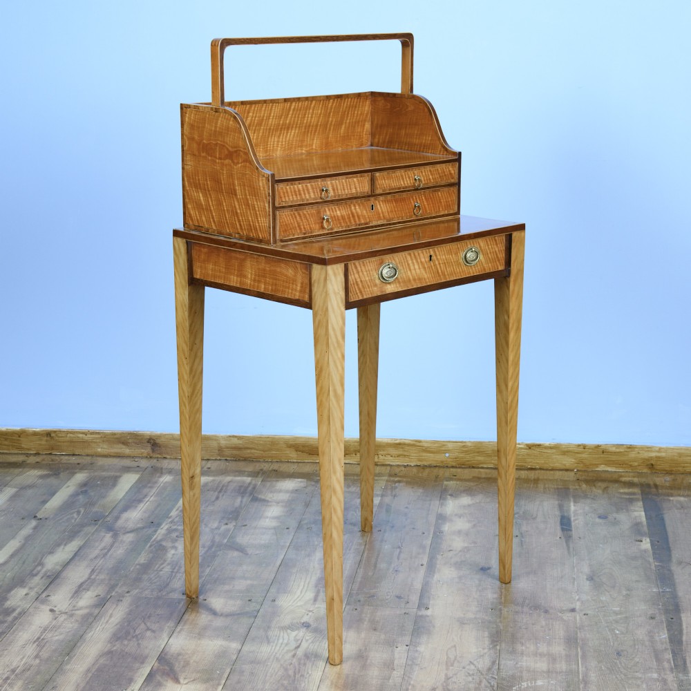 An 18th-century Georgian satinwood cheveret writing table featuring slender square tapered legs, brass ring pulls, and a upper cabinet with an integrated handle. View II