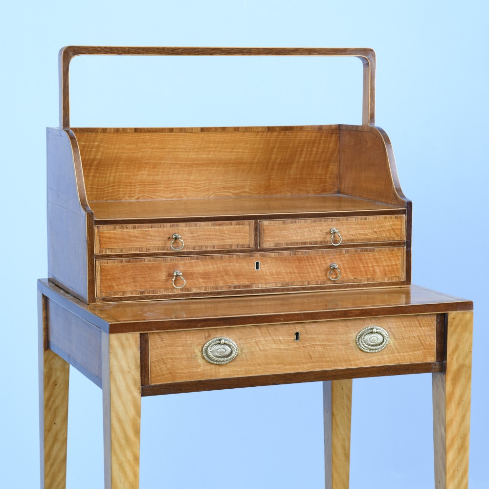 An 18th-century Georgian satinwood cheveret writing table featuring slender square tapered legs, brass ring pulls, and a upper cabinet with an integrated handle. View V