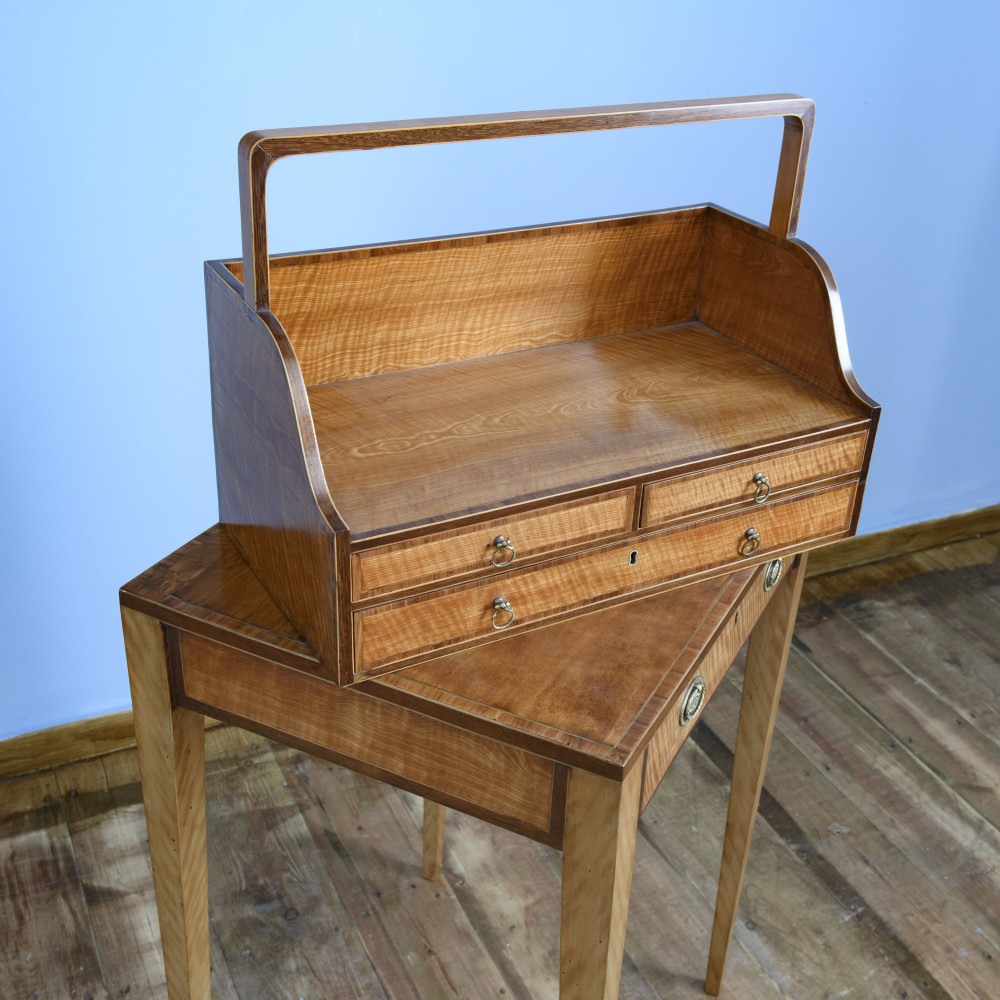 An 18th-century Georgian satinwood cheveret writing table featuring slender square tapered legs, brass ring pulls, and a upper cabinet with an integrated handle. View VII