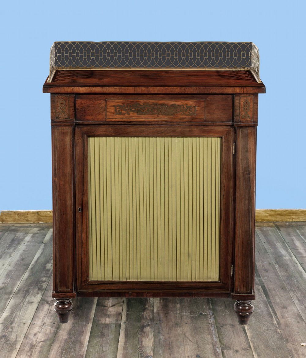 A Regency period rosewood side cabinet featuring brass floral inlay, a brass pierced gallery rail, and a single door with a pleated fabric panel. View II