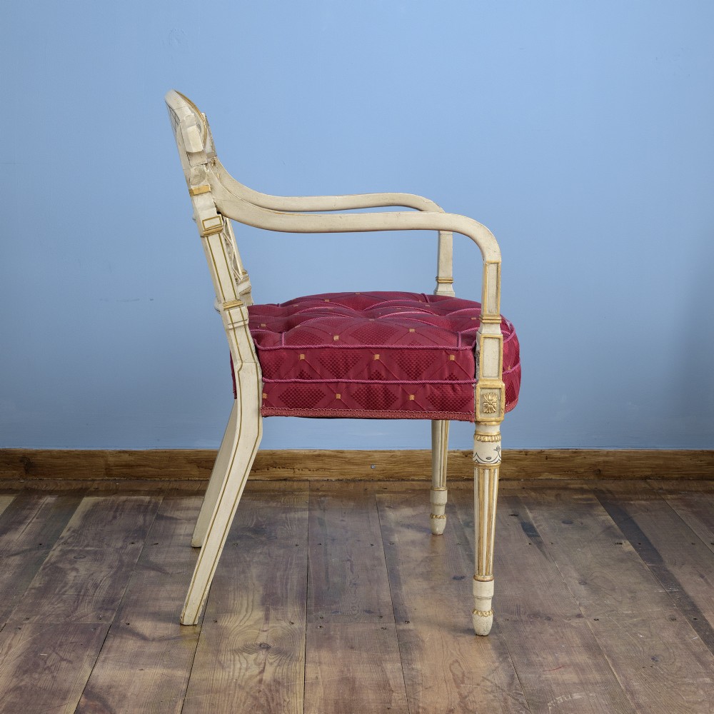 A pair of cream-painted and parcel-gilt Neoclassical armchairs featuring pierced lattice backs, painted oval medallions, and crimson fabric seats. View VI