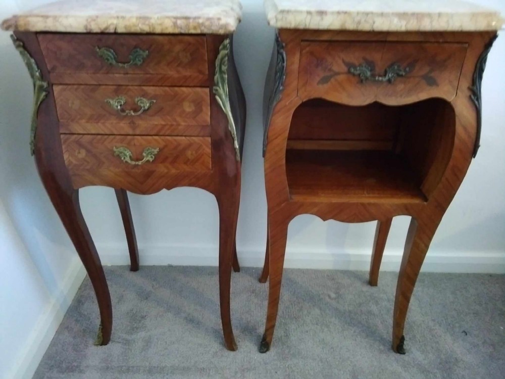 Pair of 1920s French Rococo style bombe bedside cabinets featuring shaped marble tops, marquetry veneers, and ornate brass mounts.