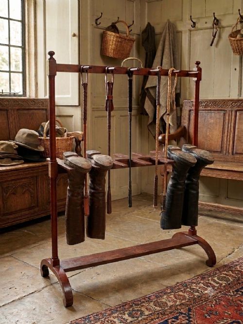 An antique mahogany whip and boot stand featuring turned upper pegs, a brass handle, shaped middle boot apertures, and swept trestle feet. View IV