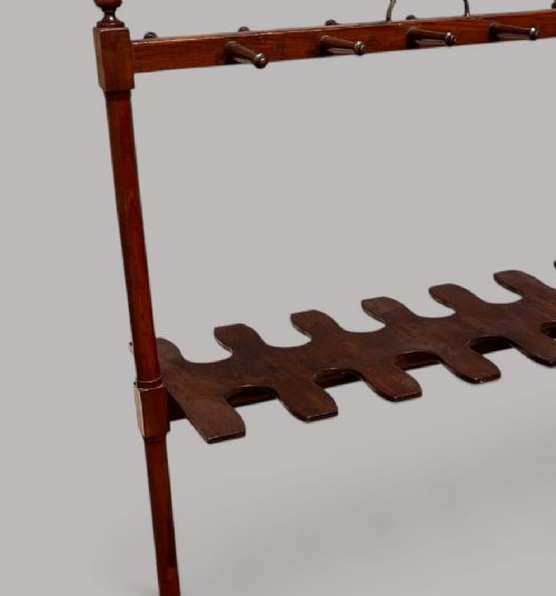 An antique mahogany whip and boot stand featuring turned upper pegs, a brass handle, shaped middle boot apertures, and swept trestle feet. View VIII