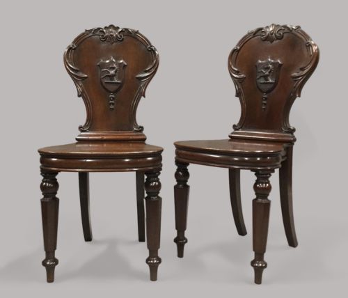 George IV substantial pair of mahogany hall chairs; with well carved Hippocampus armorials