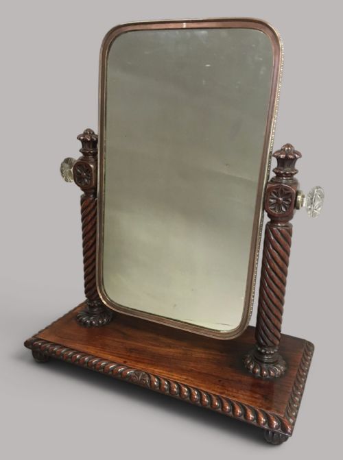 fig 1. An antique Regency Anglo-Indian dark padouk timber dressing mirror featuring spiral twist columns, carved rope-twist base trim, glass side knobs, and a tall rectangular mirror plate.