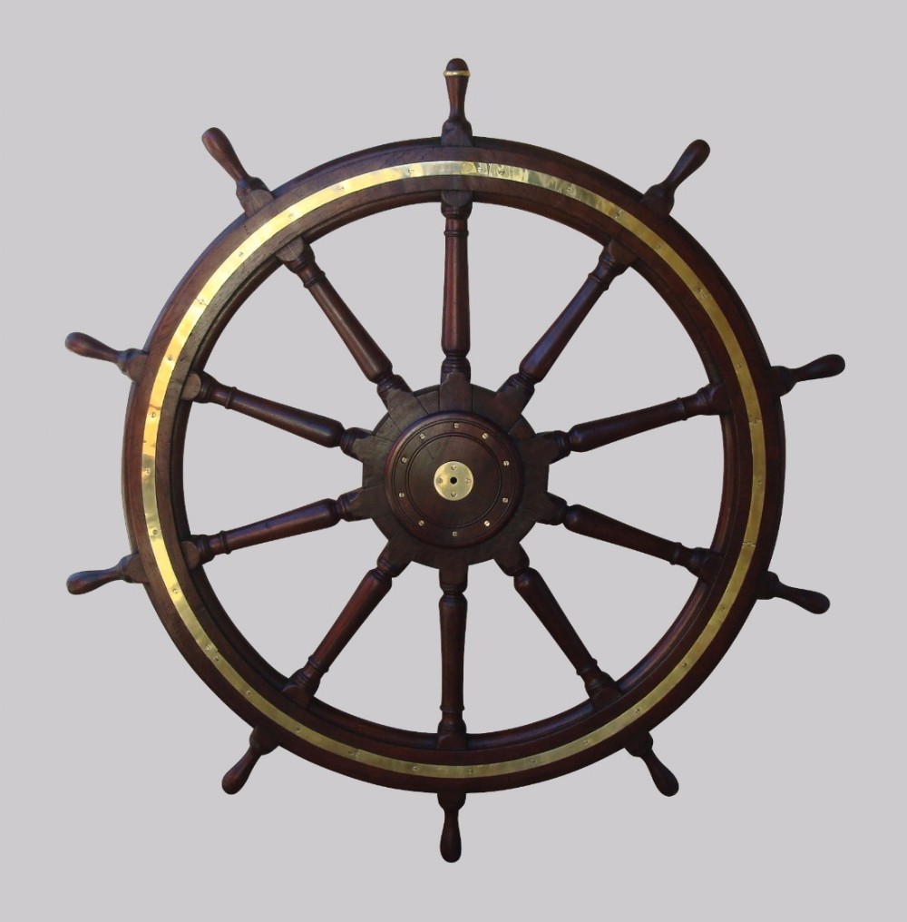 A 19th-century dark teak ships wheel featuring ten turned spokes and a central brass inlay ring and hub.