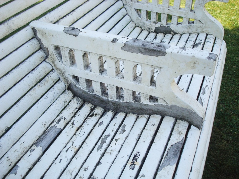 A distressed white painted slatted teak garden seat featuring a curved backrest, central divider armrest, and lattice detailed sides. View VIII