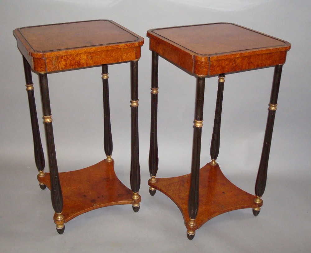 A pair of tall Regency occasional tables featuring square amboyna tops, ebonised turned legs with gilt accents, and concave undertiers. View II