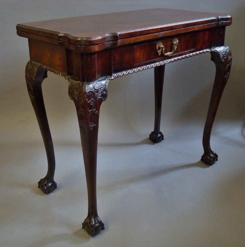 A George III mahogany card table with a fold-over top, a single frieze drawer, carved cabriole legs, and claw and ball feet. View V