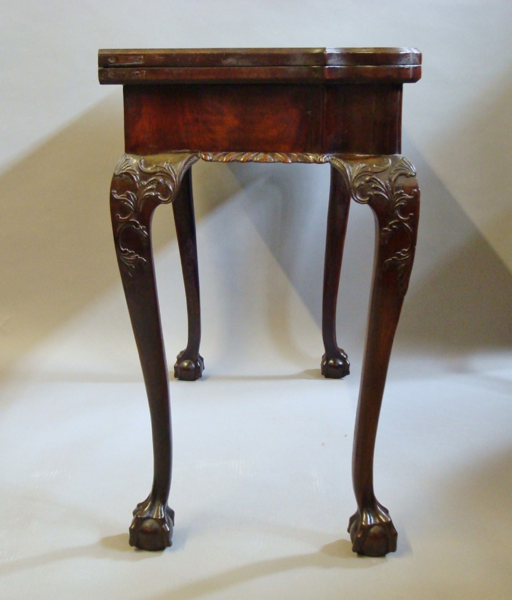 A George III mahogany card table with a fold-over top, a single frieze drawer, carved cabriole legs, and claw and ball feet. View VI