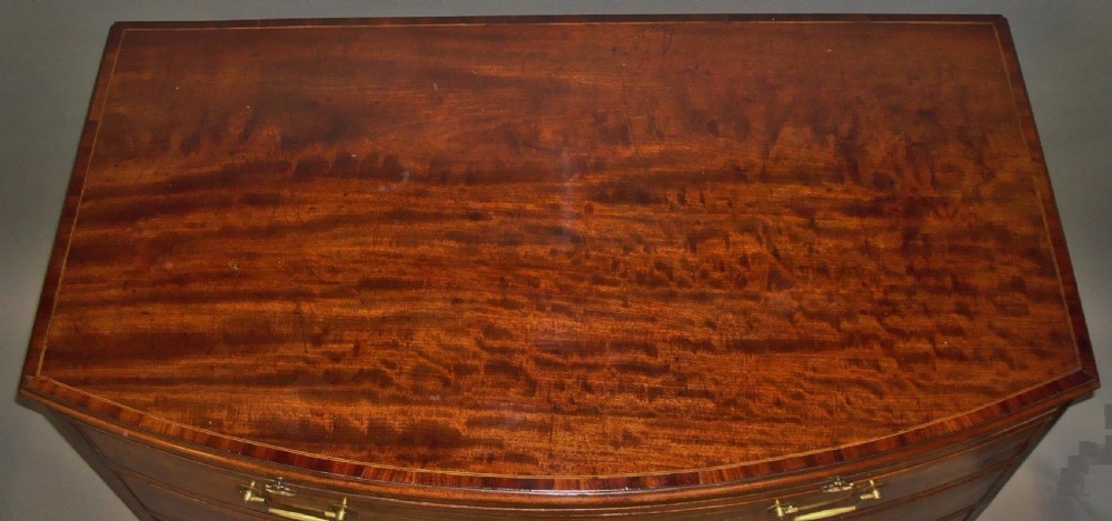 A George III mahogany bowfront chest of drawers featuring four graduated drawers with brass handles and splay feet. View III