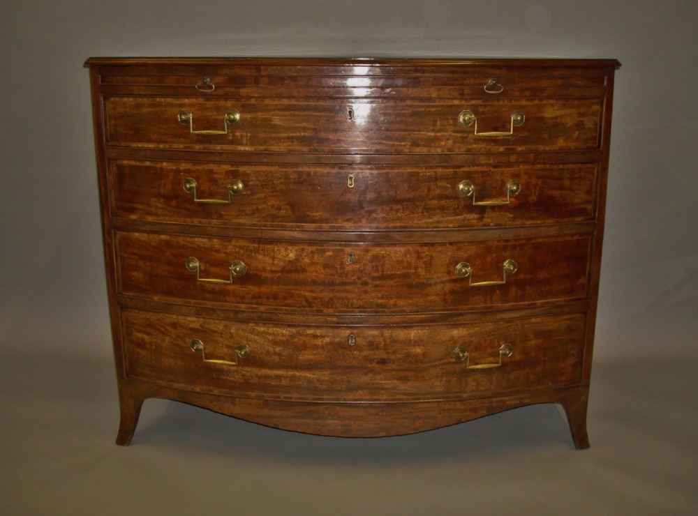 A George III mahogany bowfront chest of drawers featuring four graduated drawers with brass handles and splay feet. View V