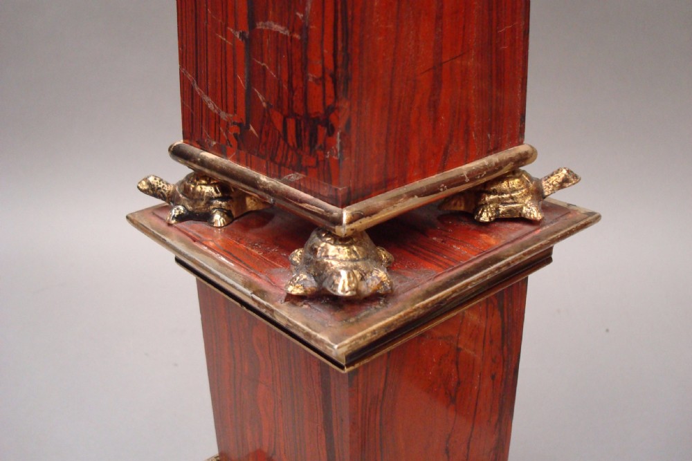 A pair of red marble obelisks featuring gilt metal collars and stepped bases. View II
