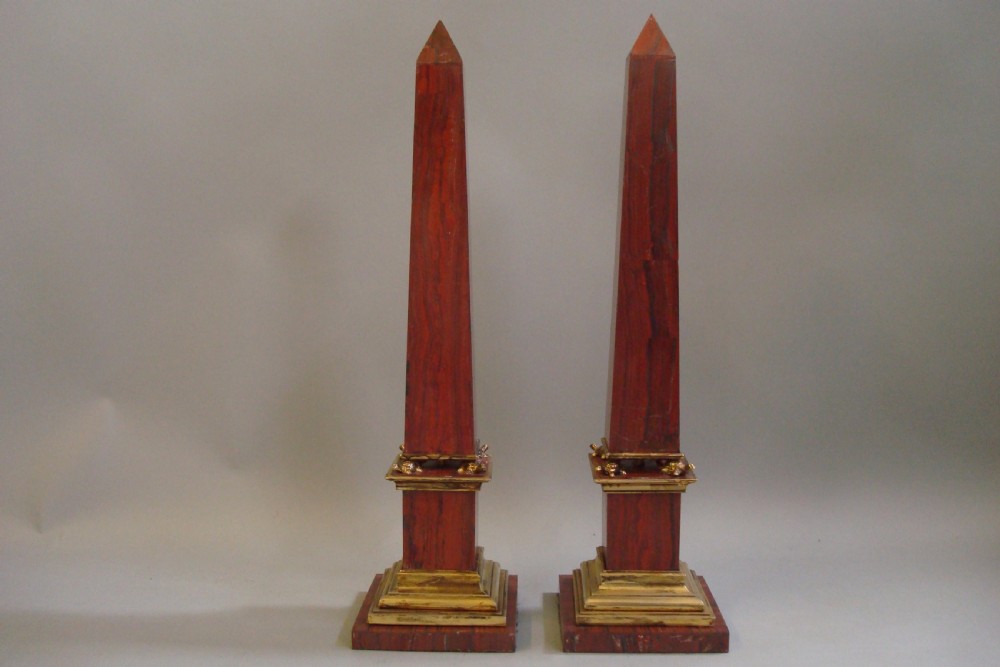 A pair of red marble obelisks featuring gilt metal collars and stepped bases. View III