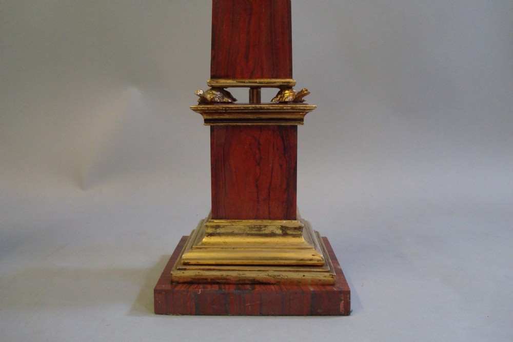 A pair of red marble obelisks featuring gilt metal collars and stepped bases. View IV