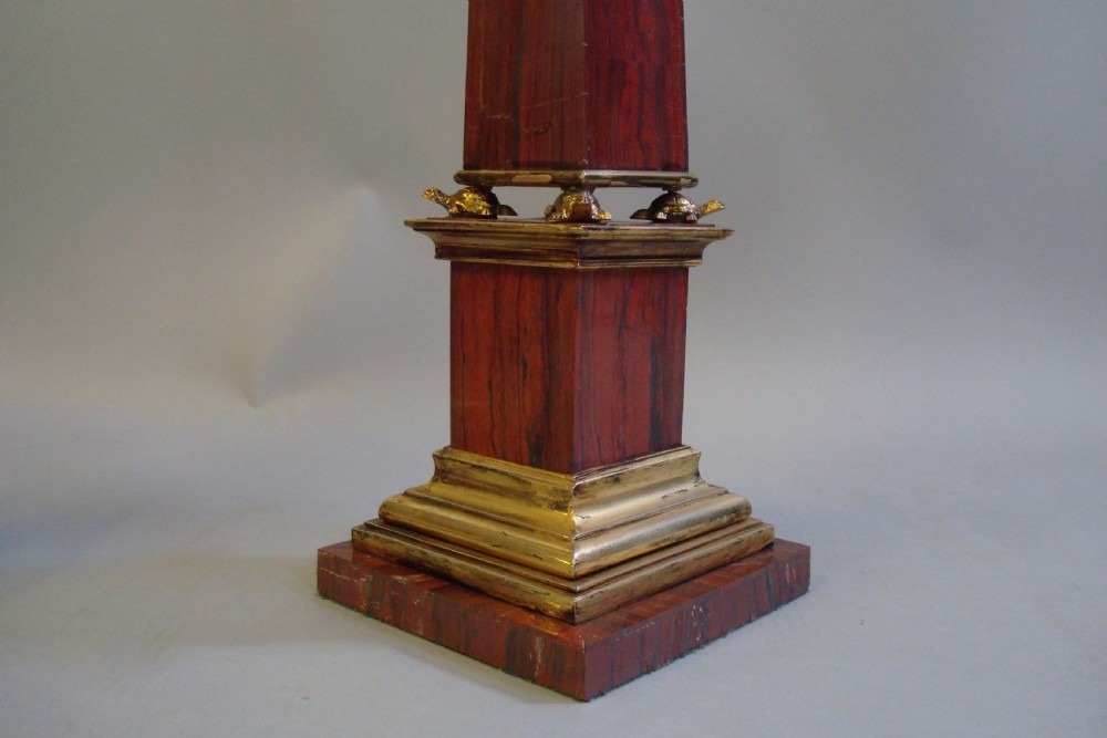 A pair of red marble obelisks featuring gilt metal collars and stepped bases. View V