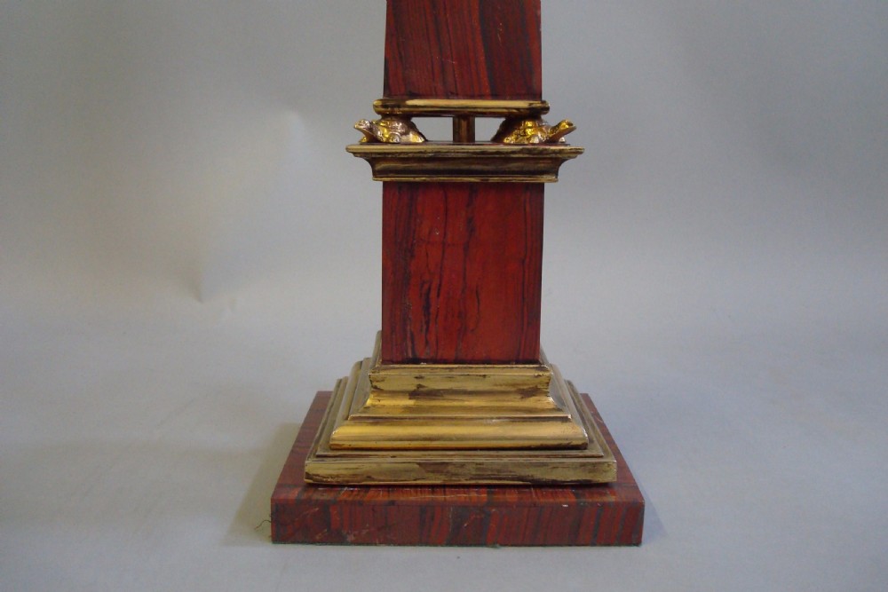 A pair of red marble obelisks featuring gilt metal collars and stepped bases. View VII