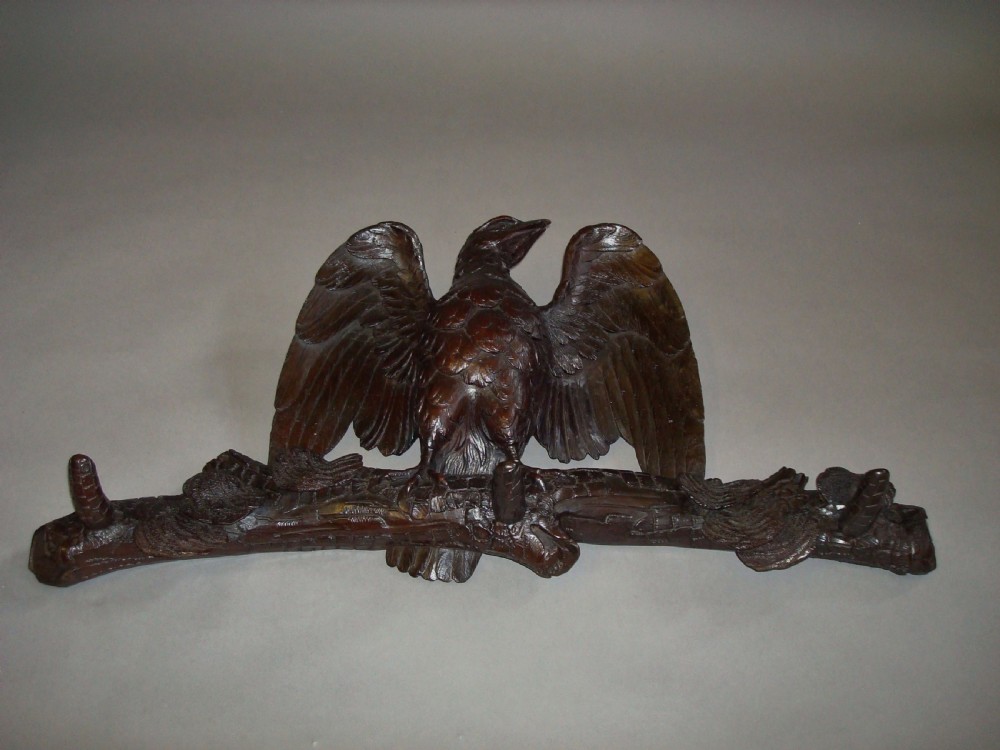 A 19th-century dark carved wood coat rack featuring an eagle with outstretched wings perched on a rustic branch with integral hanging pegs. View VII