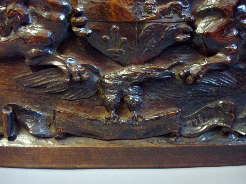 A rectangular carved dark walnut panel featuring a central coat of arms flanked by mythical beasts and foliate scrollwork. View V