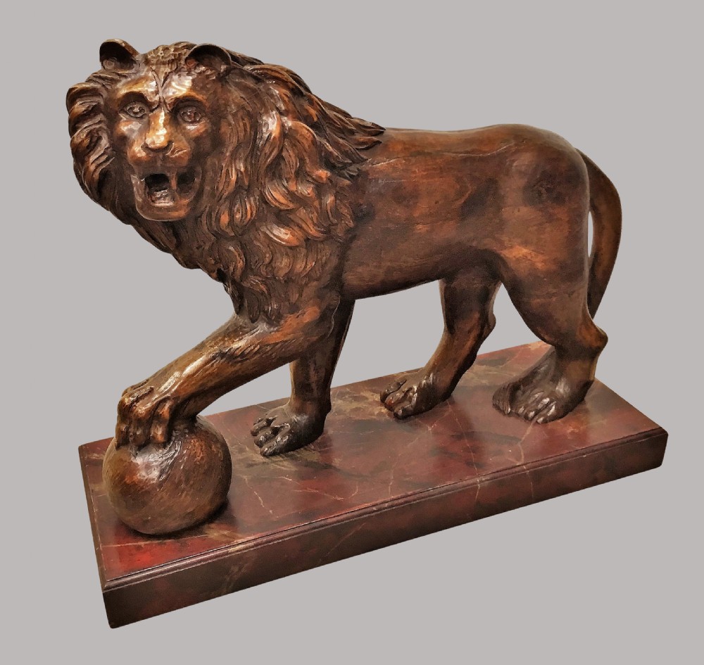 A pair of nineteenth-century carved wooden Medici lions depicted standing with one paw resting on a sphere, mounted on reddish marbled rectangular bases. View IX