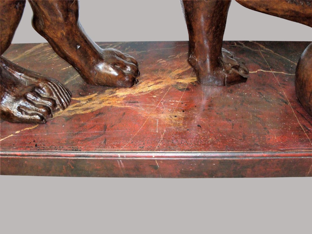 A pair of nineteenth-century carved wooden Medici lions depicted standing with one paw resting on a sphere, mounted on reddish marbled rectangular bases. View XV